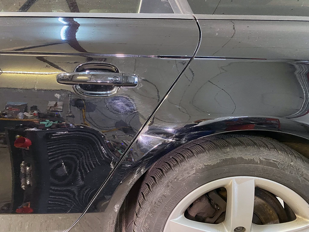 Schwarzer Audi mit sichtbarem Seitenschaden vor der Reparatur bei Autohaus Marpert in Metelen.