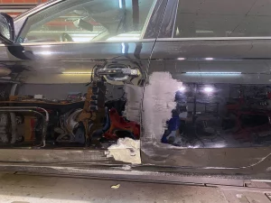 Vorbereitete Schadstellen an der Seite eines schwarzen Audi vor der Autolackierung in Metelen.
