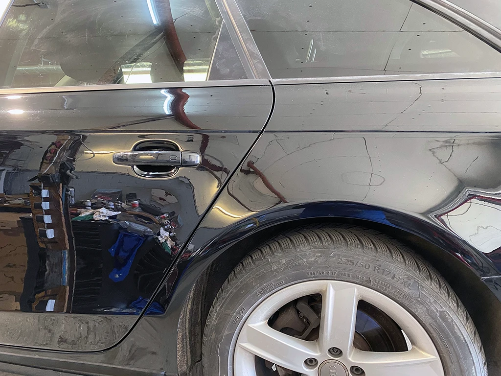 Reparierter Seitenbereich eines schwarzen Audi nach Karosserieinstandsetzung und Lackierung.